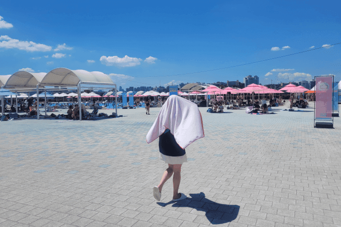 Une zone de baignade urbaine extérieure bondée où les citadins cherchent refuge contre la chaleur intense.