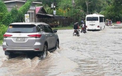 Vehicles navigating a flooded highway in Antique, illustrating the impact of Tropical Storm Crising and the southwest monsoon on daily life.