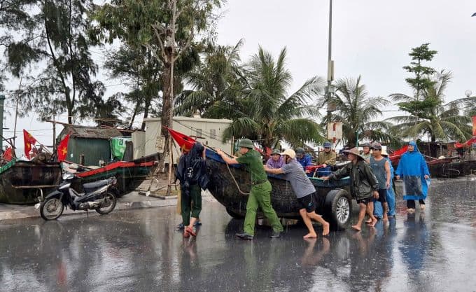Vietnamese residents and authorities moving fishing boats to safety on a wet road during Typhoon Wipha's heavy rains in Thanh Hoa.