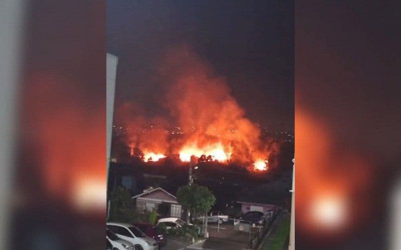 Vue nocturne d'un incendie majeur ravageant l'Ocupação Resistência e Luta à Campo Bom, avec des flammes intenses s'élevant dans le ciel.