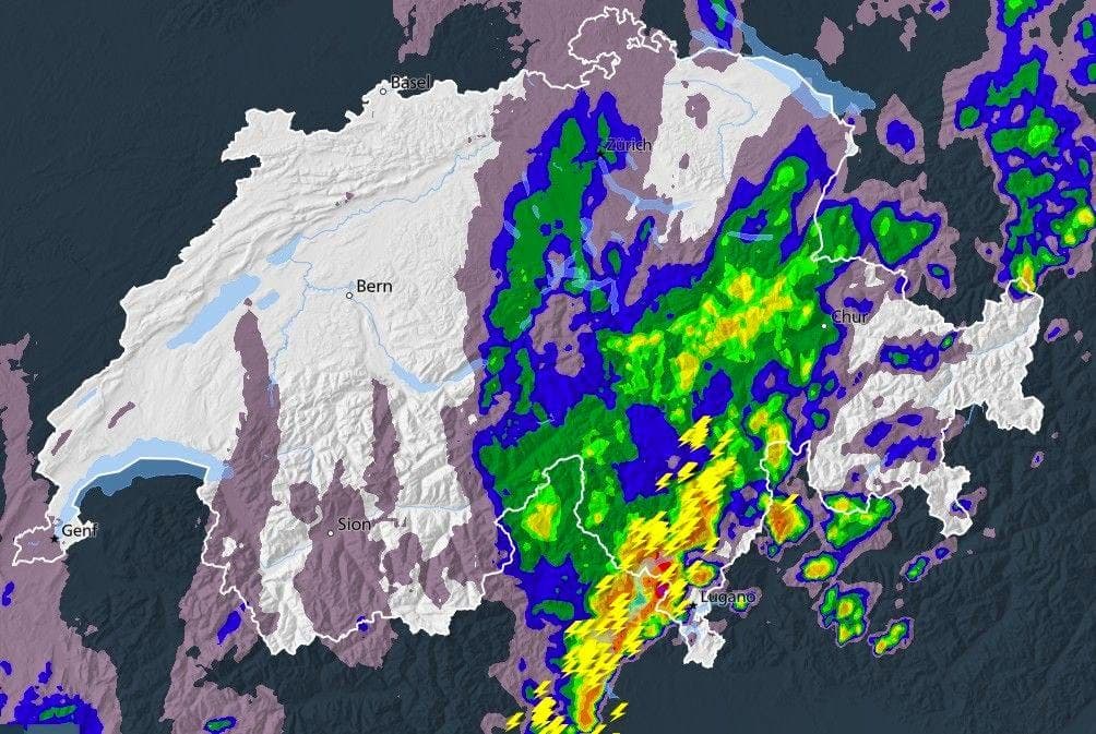 Weather radar map of Switzerland showing widespread heavy precipitation in shades of green, yellow, and red, indicating intense rainfall across much of the country.
