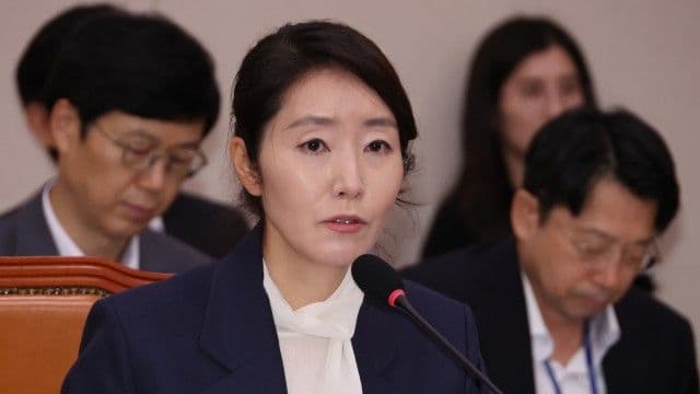 Yong Hye-in speaking at a microphone in a formal political setting, demonstrating her outspoken stance and challenge to political norms.